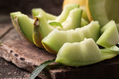 Dilimlenmiş taze kavun ve ahşap masa, sağlıklı gıda nane