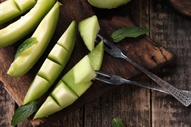 Dilimlenmiş taze kavun ve ahşap masa, sağlıklı gıda nane