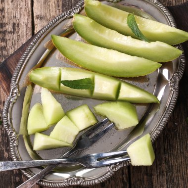 Dilimlenmiş taze kavun ve ahşap masa, sağlıklı gıda nane