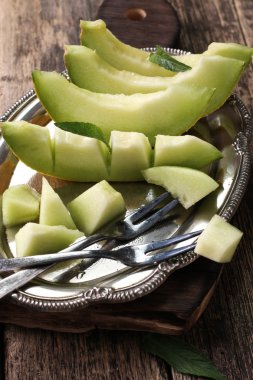 Dilimlenmiş taze kavun ve ahşap masa, sağlıklı gıda nane