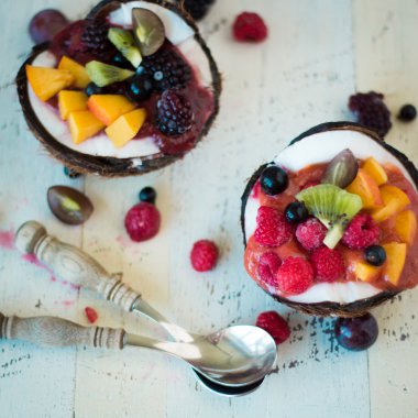 ahşap arka plan üzerinde iki Hindistan cevizi yaban mersini ve çilek servis.