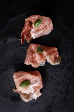 Fesleğenli domates ahşap kesme tahtası, antika arka plan üzerinde ince dilim jambon ile karışık