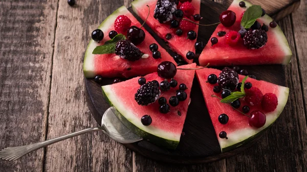 Färgglada tropiska frukter vattenmelon pizza toppad med bär som är skuren i segment — Stockfoto