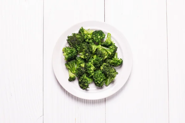 Bunch of fresh green broccoli on brown plate over wooden background — Stock Photo, Image