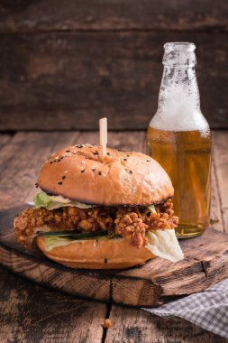 Ahşap bir masa üzerinde bir bira ile taze ve lezzetli hamburger.