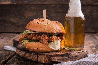 Ahşap bir masa üzerinde bir bira ile taze ve lezzetli hamburger.