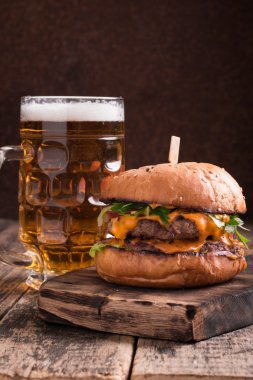 Ahşap bir masa üzerinde bir bira ile taze ve lezzetli hamburger.