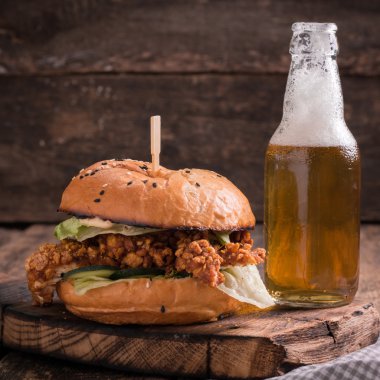 Ahşap bir masa üzerinde bir bira ile taze ve lezzetli hamburger.