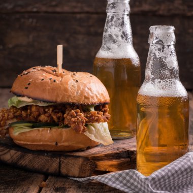 Ahşap bir masa üzerinde bir bira ile taze ve lezzetli hamburger.