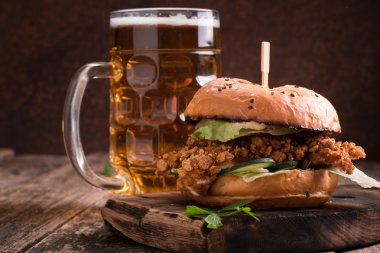 Ahşap bir masa üzerinde bir bira ile taze ve lezzetli hamburger.