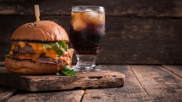 Comida rápida con hamburguesa o hamburguesa con queso, y refresco en la mesa de madera vintage — Foto de Stock