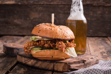 Ahşap bir masa üzerinde bir bira ile taze ve lezzetli hamburger.