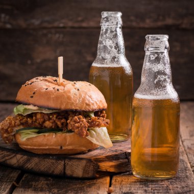 Ahşap bir masa üzerinde bir bira ile taze ve lezzetli hamburger.