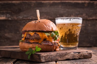 Ahşap bir masa üzerinde bir bira ile taze ve lezzetli hamburger.
