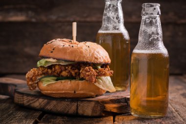 Ahşap bir masa üzerinde bir bira ile taze ve lezzetli hamburger.
