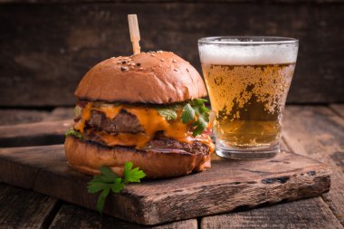 Ahşap bir masa üzerinde bir bira ile taze ve lezzetli hamburger.