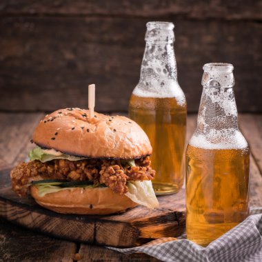 Ahşap bir masa üzerinde bir bira ile taze ve lezzetli hamburger.