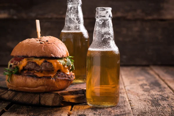 Hambúrguer fresco e saboroso com uma cerveja em uma mesa de madeira . — Fotografia de Stock