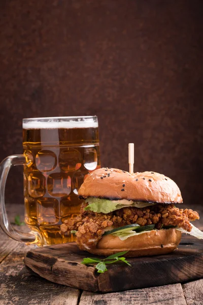 Hamburguesa fresca y sabrosa con una cerveza en una mesa de madera . — Foto de Stock