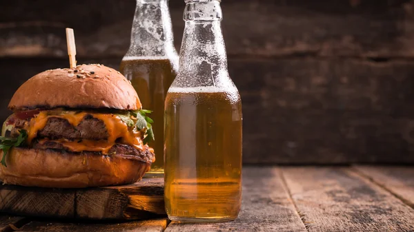 Hamburger fresco e gustoso con una birra su un tavolo di legno . — Foto Stock