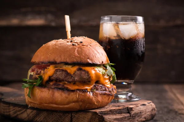 Фастфуд з бургер або чізбургер, і безалкогольний напій на старовинному дерев'яному столі — стокове фото