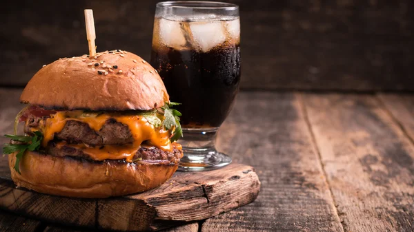 Comida rápida con hamburguesa o hamburguesa con queso, y refresco en la mesa de madera vintage — Foto de Stock