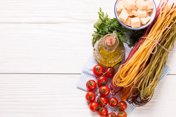 Color vegetal Pasta, aceite, tomates, queso sobre mesa de madera. comida italiana —  Fotos de Stock