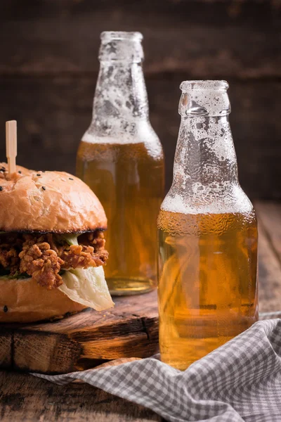 Hamburguesa fresca y sabrosa con una cerveza en una mesa de madera . — Foto de Stock