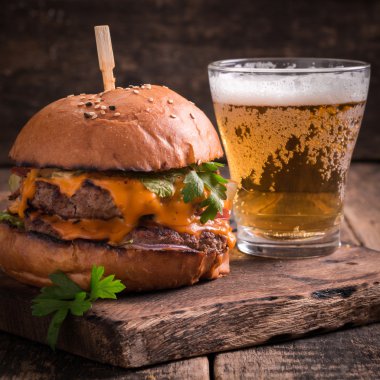 Ahşap bir masa üzerinde bir bira ile taze ve lezzetli hamburger.