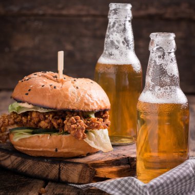 Ahşap bir masa üzerinde bir bira ile taze ve lezzetli hamburger.