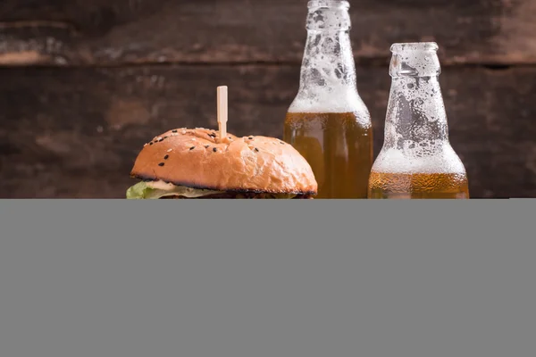 Свіжий і смачний гамбургер з пивом на дерев'яному столі . — стокове фото