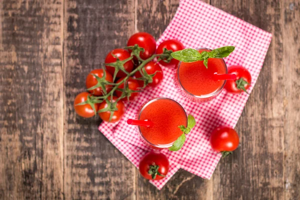 Tomatensap en verse tomaten op een houten achtergrond — Stockfoto