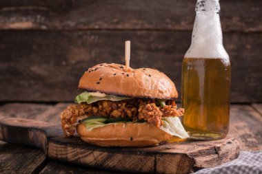 Ahşap bir masa üzerinde bir bira ile taze ve lezzetli hamburger.