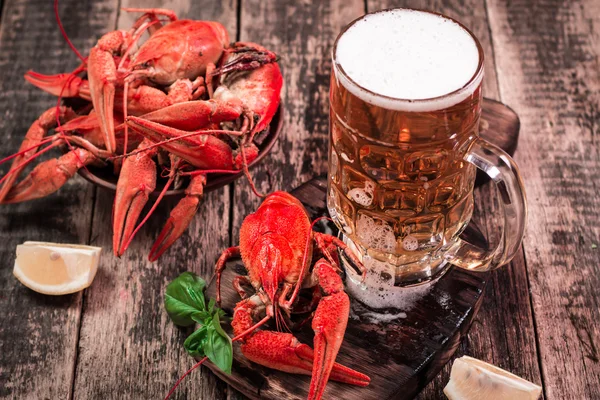 Lagosta fervida e cerveja em um fundo de madeira — Fotografia de Stock