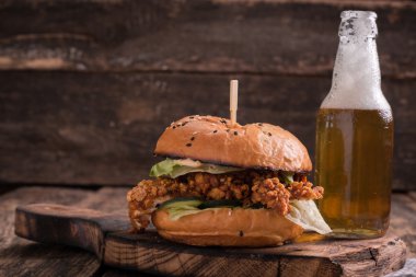 Ahşap bir masa üzerinde bir bira ile taze ve lezzetli hamburger.