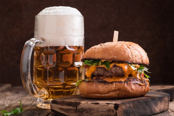 Čerstvé a chutné hamburger s pivem na dřevěný stůl. — Stock fotografie