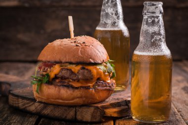 Ahşap bir masa üzerinde bir bira ile taze ve lezzetli hamburger.