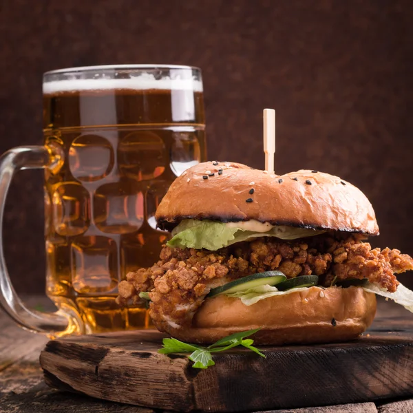 Vers en smakelijk hamburger met een biertje op een houten tafel. — Stockfoto