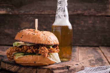 Ahşap bir masa üzerinde bir bira ile taze ve lezzetli hamburger.