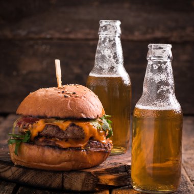 Ahşap bir masa üzerinde bir bira ile taze ve lezzetli hamburger.