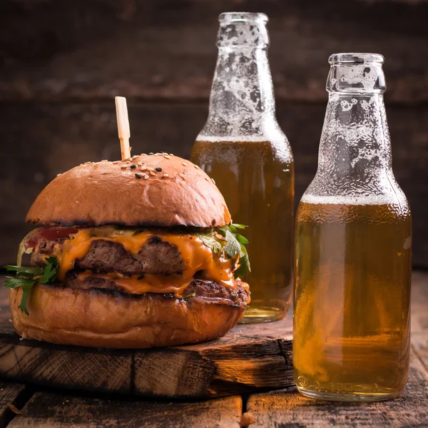 Hamburguesa fresca y sabrosa con una cerveza en una mesa de madera . — Foto de Stock