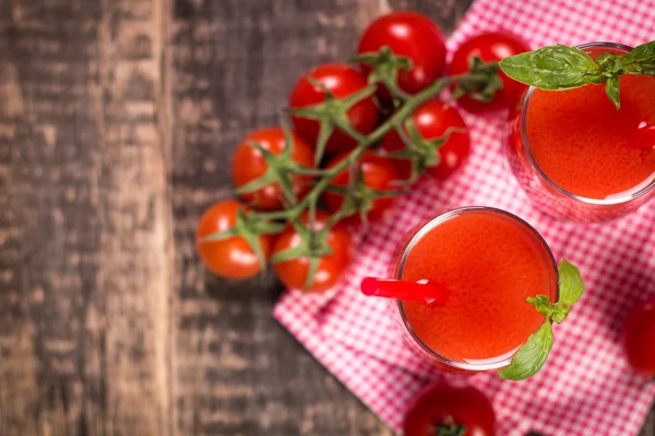 Tomatensap en verse tomaten op een houten achtergrond — Stockfoto