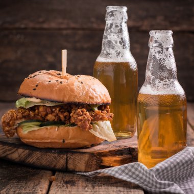 Ahşap bir masa üzerinde bir bira ile taze ve lezzetli hamburger.