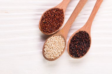 Kırmızı, siyah ve beyaz quinoa tohumları ahşap zemin, sağlıklı gıda.
