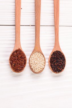 Ahşap arka planda kırmızı, siyah ve beyaz kinoa tohumları