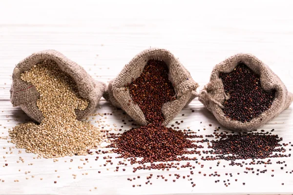 Semillas de quinua rojas, negras y blancas sobre un fondo de madera, comida saludable . — Foto de Stock