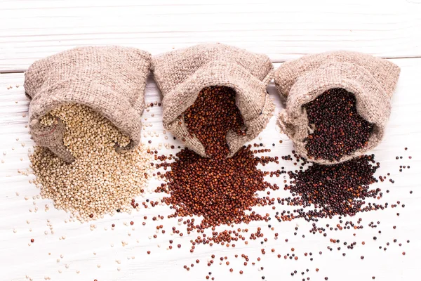 Semillas de quinua rojas, negras y blancas sobre un fondo de madera, comida saludable . — Foto de Stock