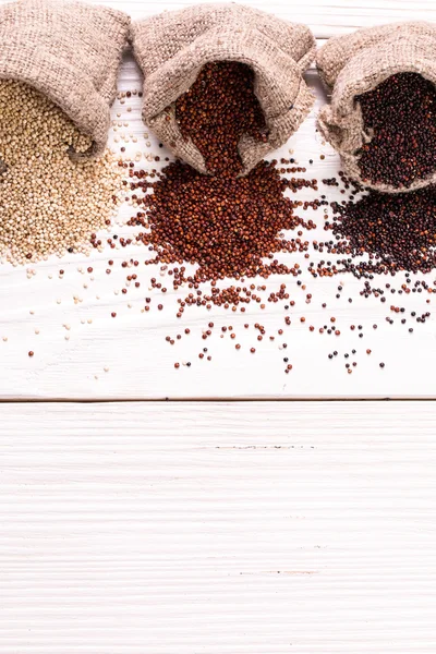 Sementes de quinoa vermelhas, pretas e brancas em um fundo de madeira, alimentos saudáveis . — Fotografia de Stock
