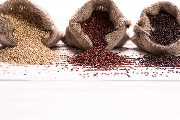 Sementes de quinoa vermelhas, pretas e brancas em um fundo de madeira, alimentos saudáveis . — Fotografia de Stock