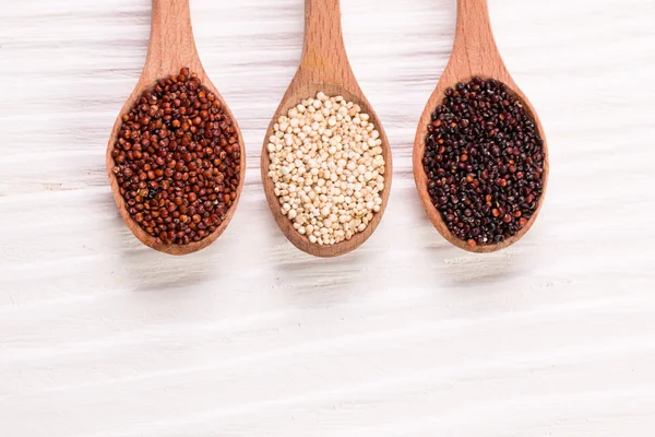 Semințe de quinoa roșu, negru și alb pe un fundal din lemn — Fotografie, imagine de stoc
